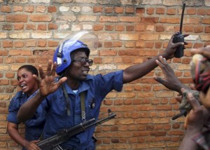 A policeman tries to protect a female police officer accused of shooting a protestor in the Buterere neighbourhood of Bujumbura, Burundi, May 12, 2015. Protestors opposed to the president's decision to run for a third term chased, beat and stoned the woman, who was later handed back to the police. REUTERS/Goran Tomasevic