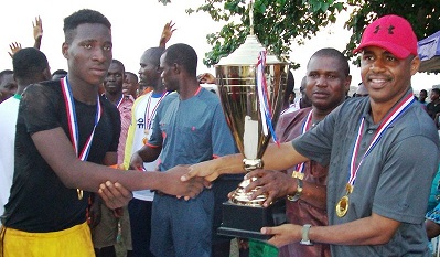 THE COMMANDER, ONITSHA MILITARY CANTONMENT, COL. MOHAMMED BELLO PRESENTING A TROPHY TO THE CAPTAIN OF BARCA FC, BARRACKS, MASTER CHIGOZIE ONYEKACHI DURING THE COMMANDERS CUP, FINALS, MALE FOOTBALL COMPETITION