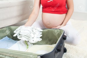 Pregnant-woman-is-getting-ready-for-the-maternity-hospital-packing-baby-clothes--Stock-Photo
