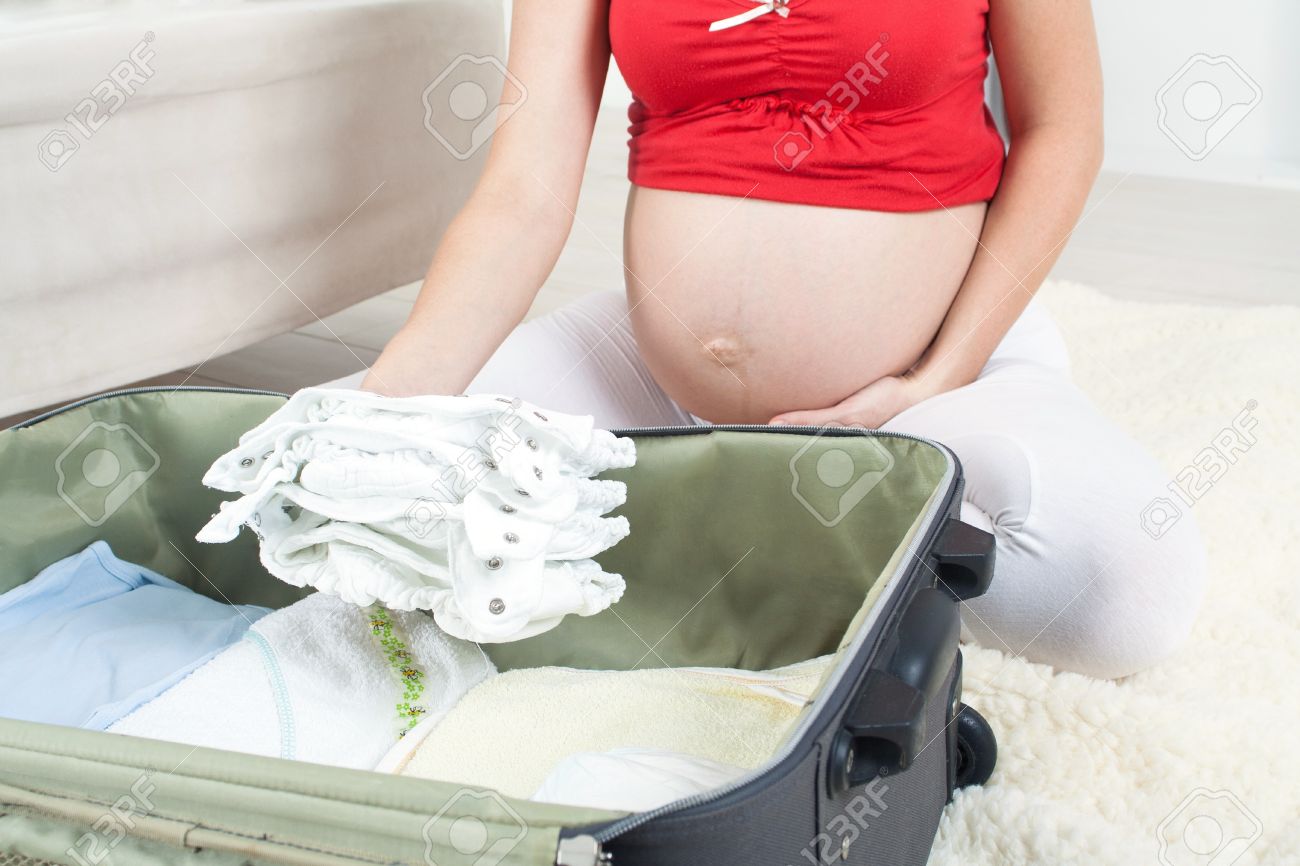 Pregnant woman is getting ready for the maternity hospital packing baby clothes Stock Photo
