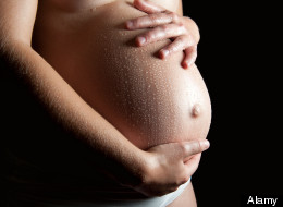 Wet belly of a beautiful pregnant woman in front of black background