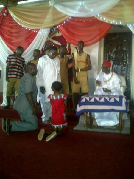 AMARACHI (IN RED) KNEELING BEFORE THE OBA