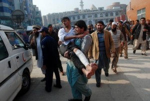 A man carries a student, who was injured during an attack by Taliban gunmen on the Army Public School, after he received treatment at a hospital in Peshawar