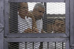 Al Jazeera journalists (L-R) Peter Greste, Mohammed Fahmy and Baher Mohamed stand behind bars at a court in Cairo June 1, 2014. REUTERS/Asmaa Waguih