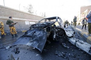 Policemen look at the wreckage of a car at the scene of a car bomb outside the police college in Sanaa
