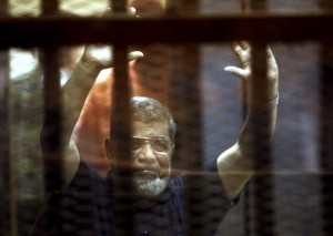 Former Egyptian President Mohamed Mursi reacts behind bars with other Muslim Brotherhood members at a court in the outskirts of Cairo, Egypt May 16, 2015.REUTERS/Mohamed Abd El Ghany