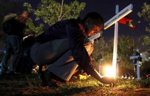 A woman lights a candle on a wooden cross after a memorial concert for the Garissa university students who were killed during an attack by gunmen, at the "Freedom Corner" in Kenya's capital Nairobi April 14, 2015. REUTERS/Thomas Mukoya
