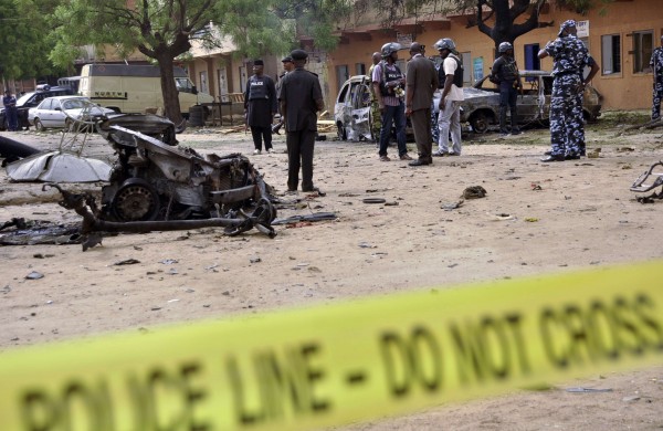 Policemen stand near damaged vehicles in Sabon Gari, Kano May 19, 2014. A suicide car bomber killed five people on a street of popular bars and restaurants in the northern Nigerian city of Kano on Sunday evening, in an area mostly inhabited by southern Christians, police said. REUTERS/Stringer (NIGERIA - Tags: CIVIL UNREST)