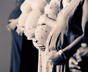 B/w line of pregnant mothers with hands on bellies