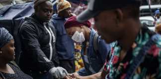 A man sprays commuters with hand sanitiser in South Africa